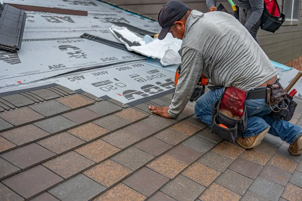 Roofing installer fastening shingles over new underlayment in Scranton, PA